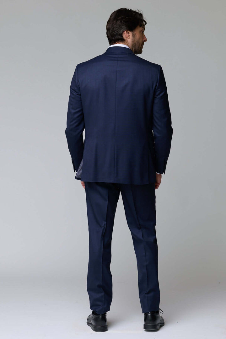 Homme portant un Complet classique deux pièces bleu, vue de dos, mettant en valeur l’élégance et la coupe ajustée du costume formel.