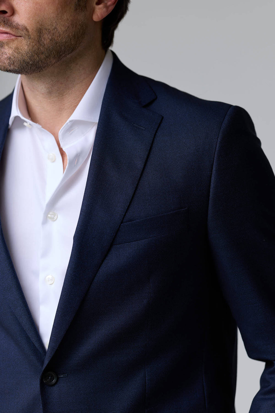Homme portant un Complet classique deux pièces bleu foncé avec une chemise blanche, idéal pour des occasions formelles et le bureau.