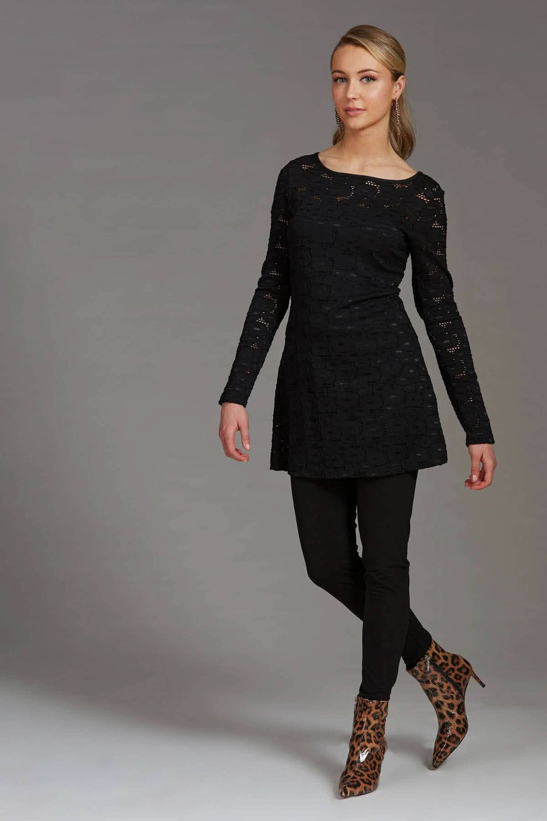 Modèle en tunique noire avec leggings, chaussures à motif léopard, pose élégante.