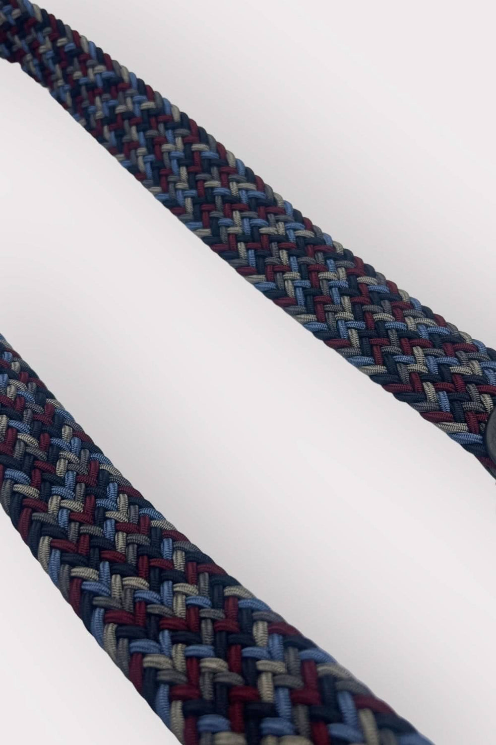 Ceinture tressée en tissu extensible avec une boucle incurvée, détail coloré et élégant.