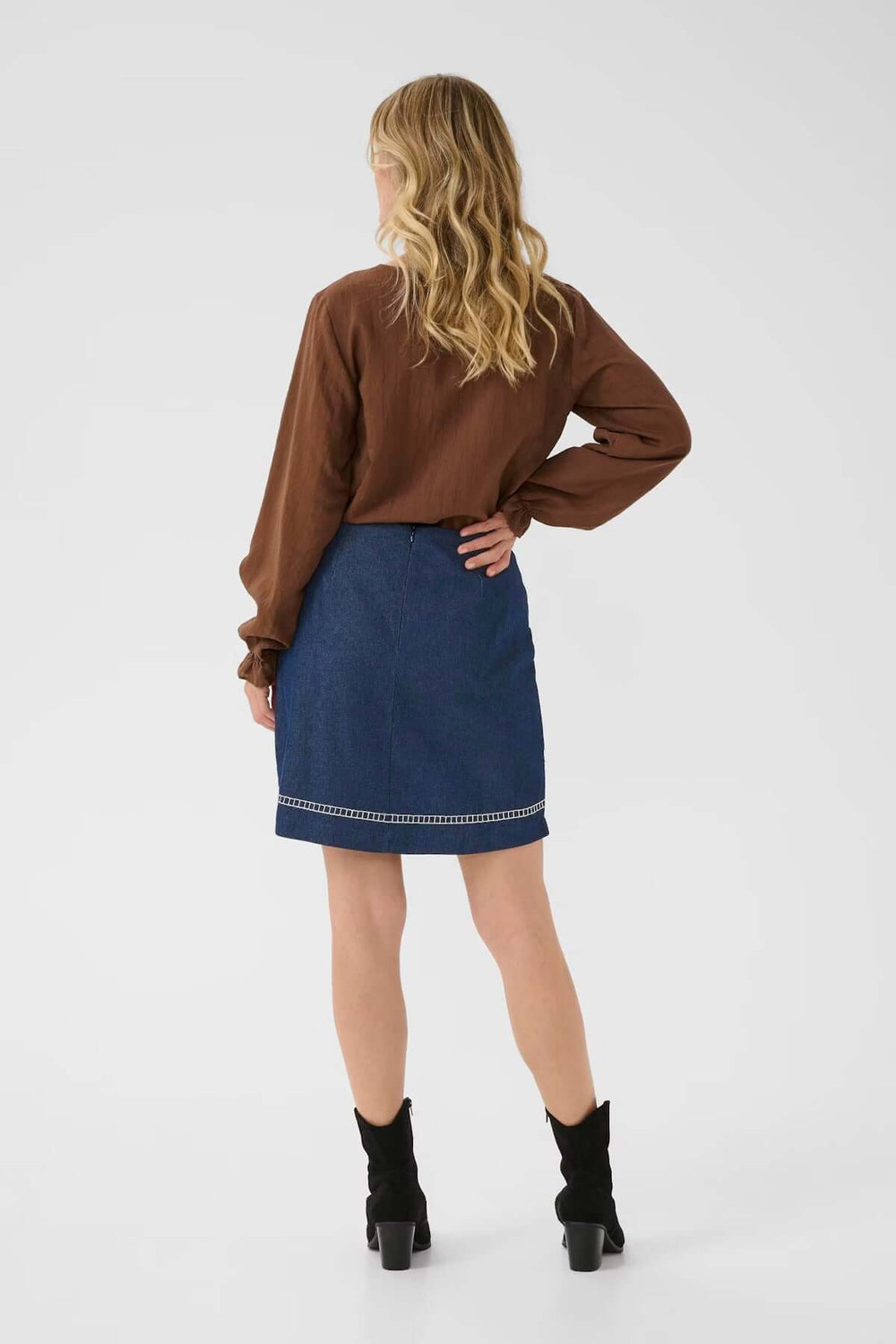 Femme portant la Jupe Gro en denim avec broderies florales, coupe droite au-dessus du genou, look bohème chic.