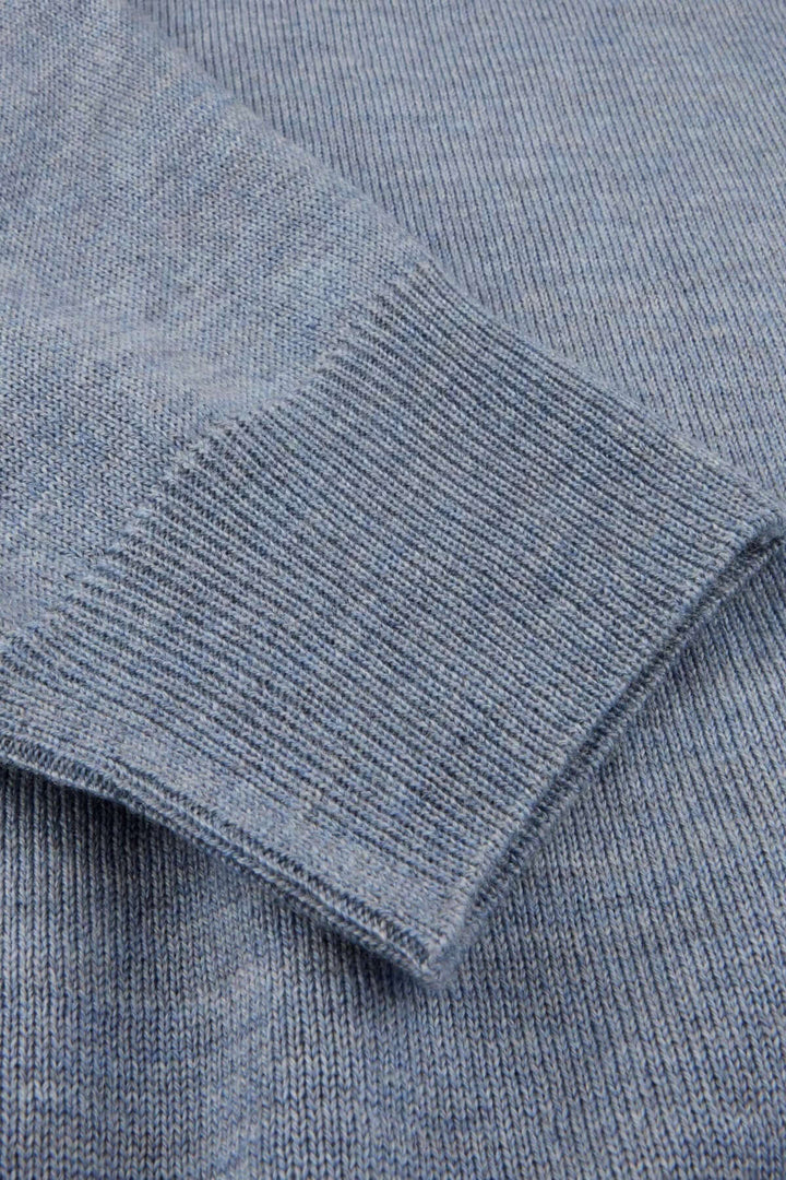 Détail chandail col rond en laine mérinos avec coudes contrastants, texture finement tricotée avec finitions côtelées.