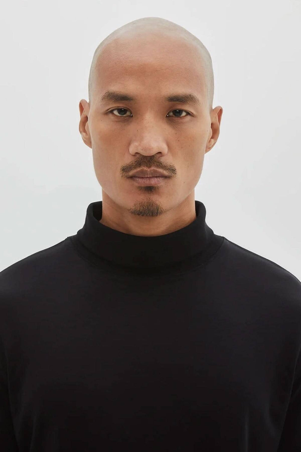 Homme portant un col roulé de coton noir, tissu doux et élégant, avec une finition moderne.