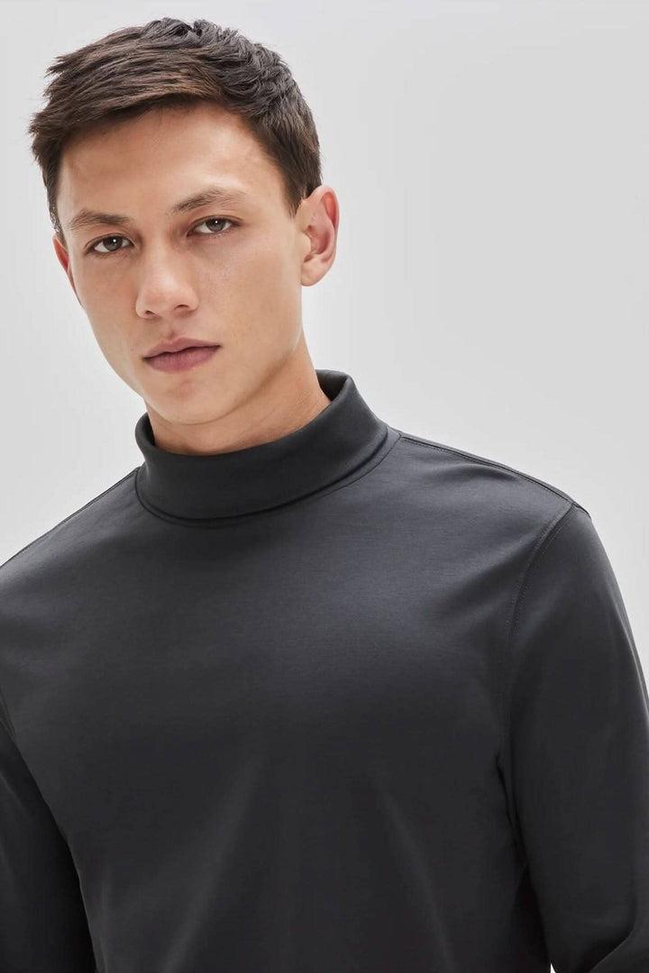 Homme portant un col roulé de coton noir, élégant et confortable, parfait pour un look décontracté et stylé.