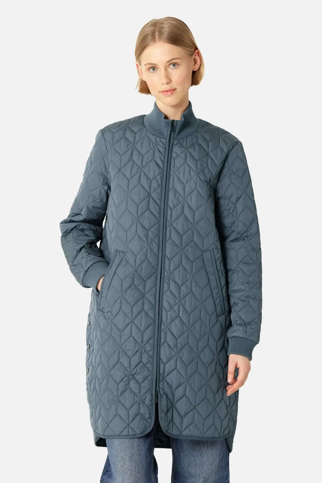 Femme portant un manteau matelassé long à col montant avec motifs géométriques, idéal pour un look urbain élégant par temps frais.