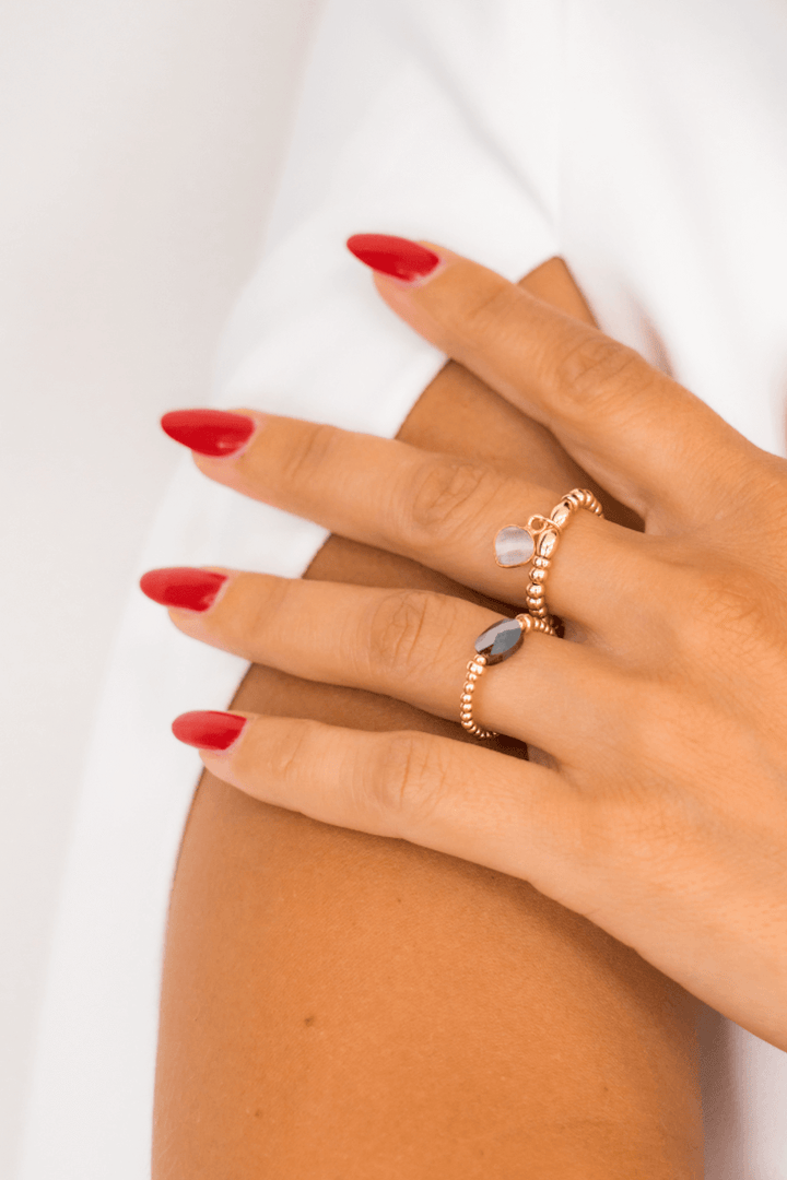 Bague en or avec pierres précieuses portée sur une main aux ongles rouges, mode élégante et raffinée.
