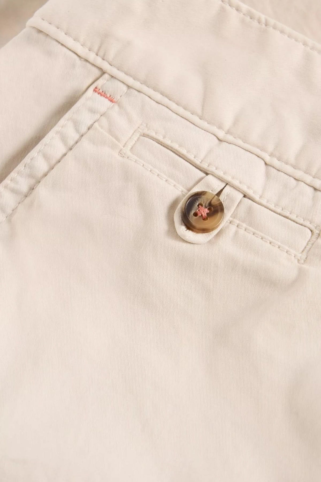 Détail d'un Bermuda en coton naturel avec bouton, parfait pour un style estival élégant.