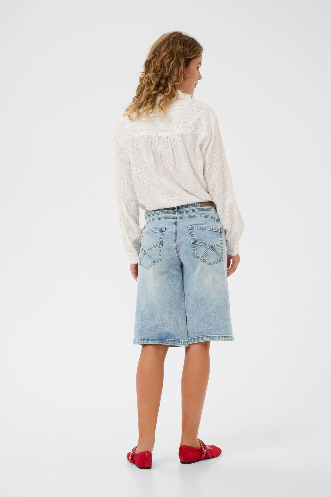 Vue arrière d'un modèle féminin portant le Bermuda Joani, un bermuda en denim à coupe droite et longueur au genou, avec détails élégants.