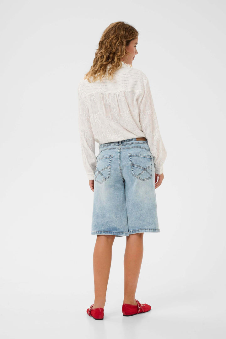 Vue arrière d'un modèle féminin portant le Bermuda Joani, un bermuda en denim à coupe droite et longueur au genou, avec détails élégants.