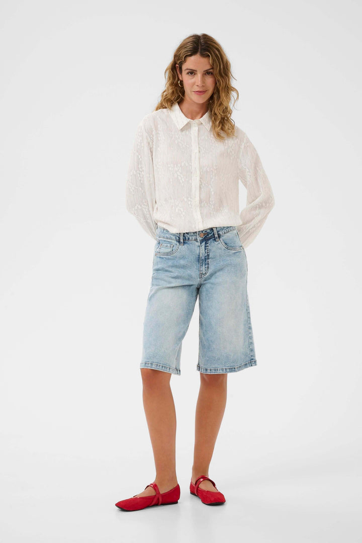 Femme portant Bermuda Joani en denim avec coupe droite et longueur au genou, offrant style décontracté et confort.