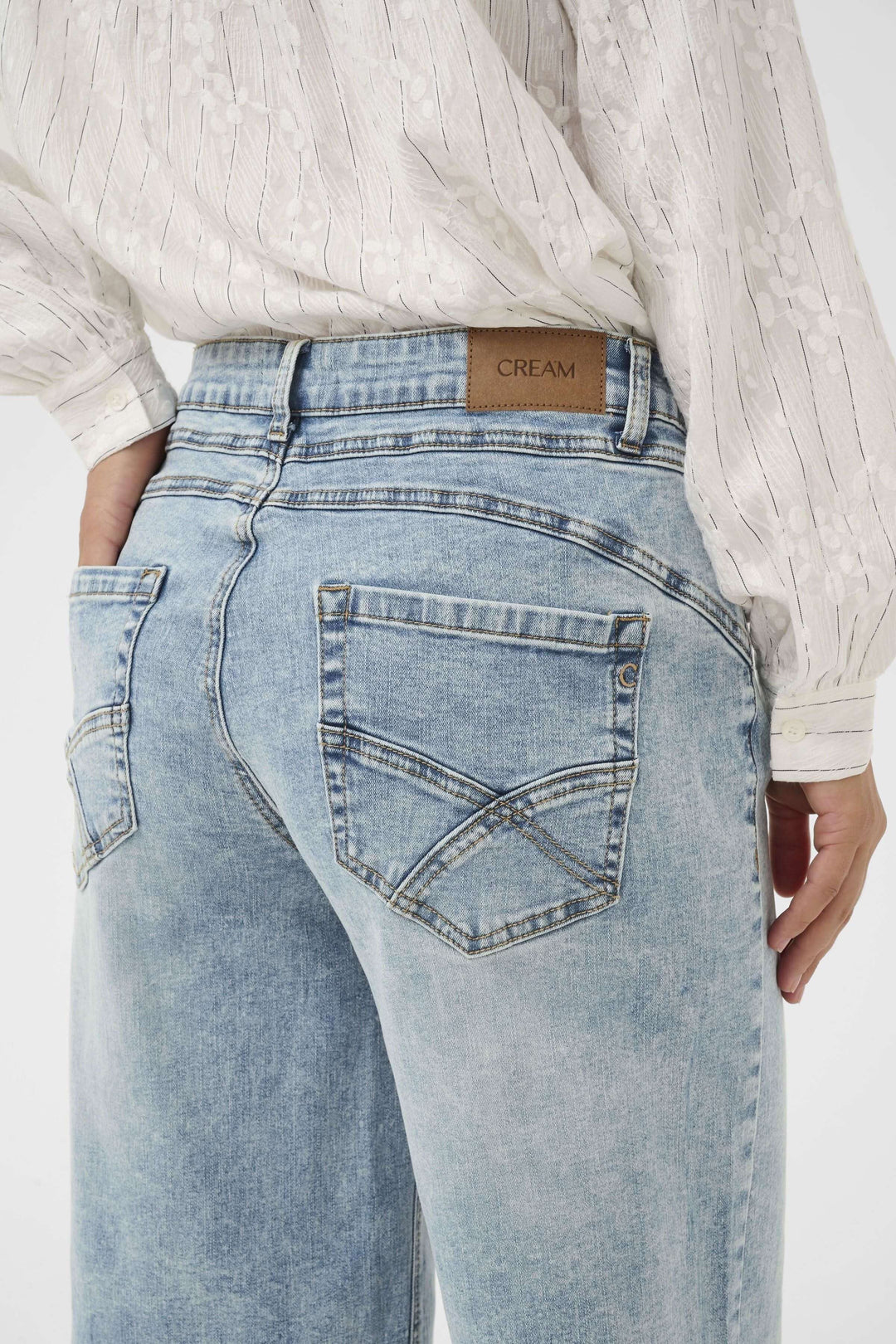 Modele en Bermuda Joani en denim bleu clair, vue arrière coupée droite, cousu structuré avec poche brodée, idéal pour le style estival.