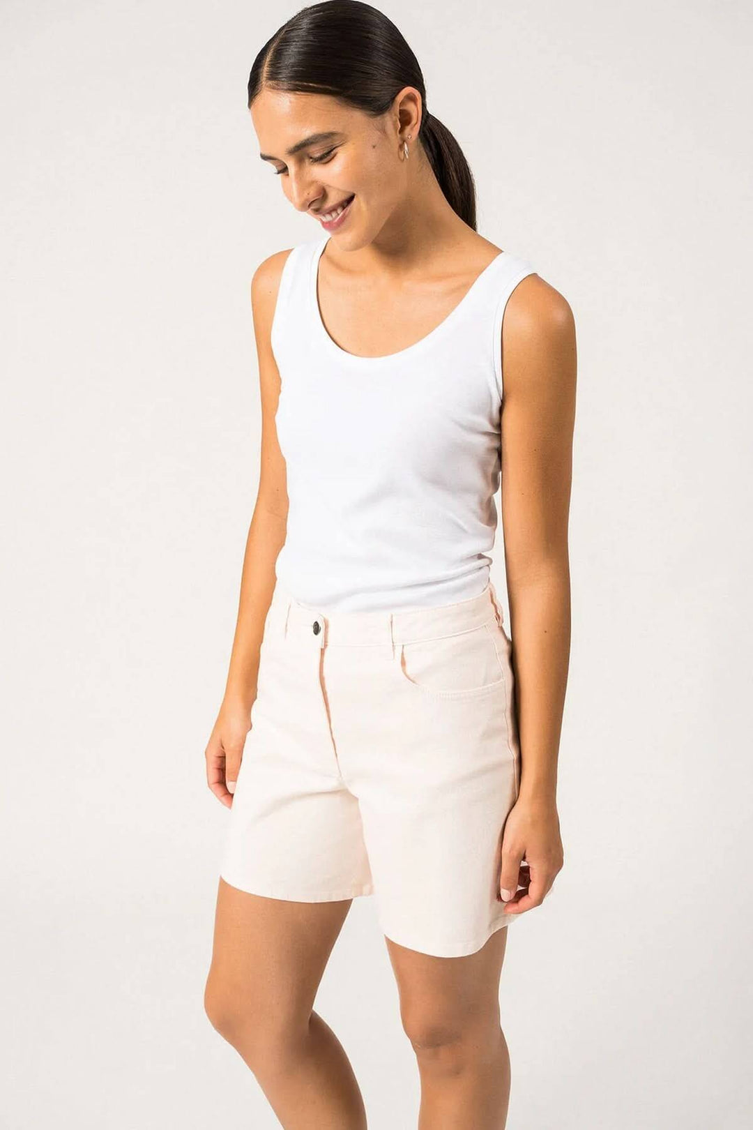 Femme portant un short Bermuda Pearl, en coton sergé, avec un top blanc, idéal pour l'été.