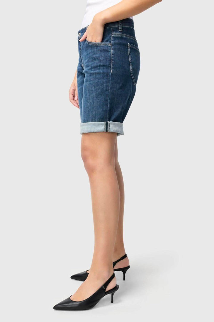 Bermuda en denim avec une coupe ajustée, un revers soigné et porté avec des escarpins élégants.