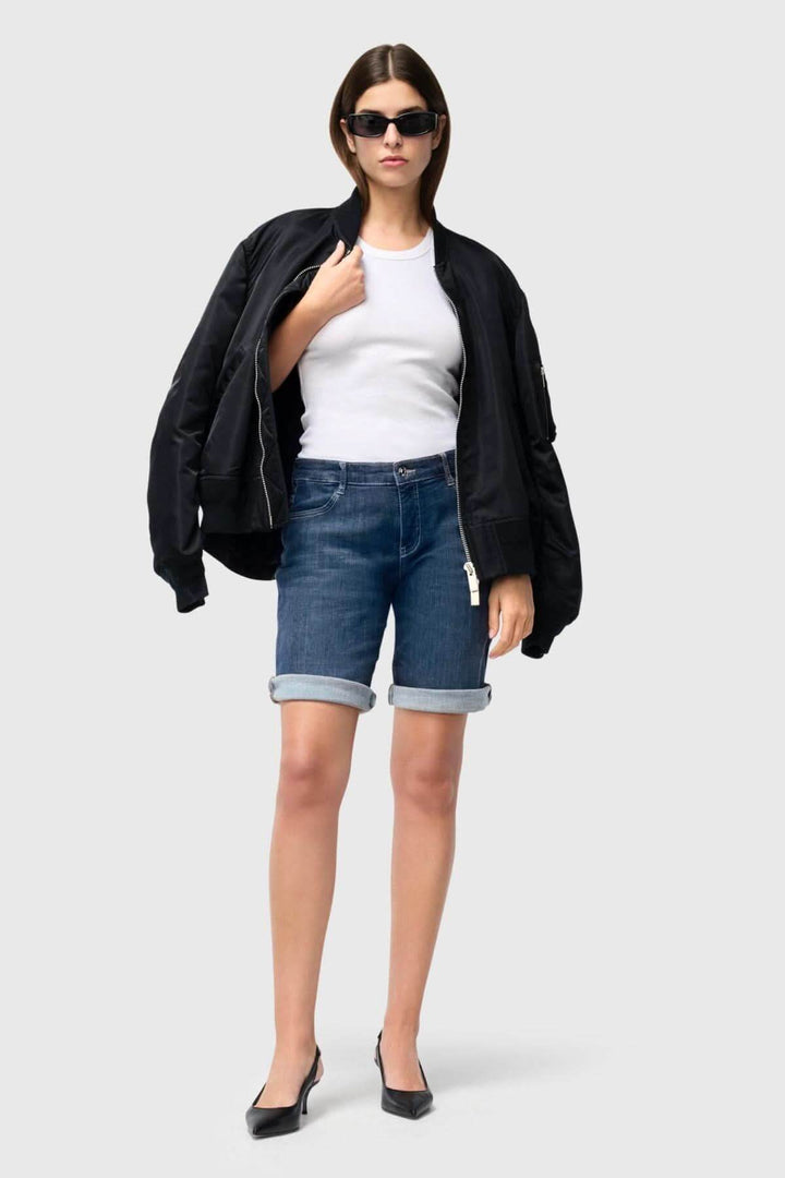 Femme en bermuda denim, débardeur blanc et veste noire, style décontracté chic pour l'été.