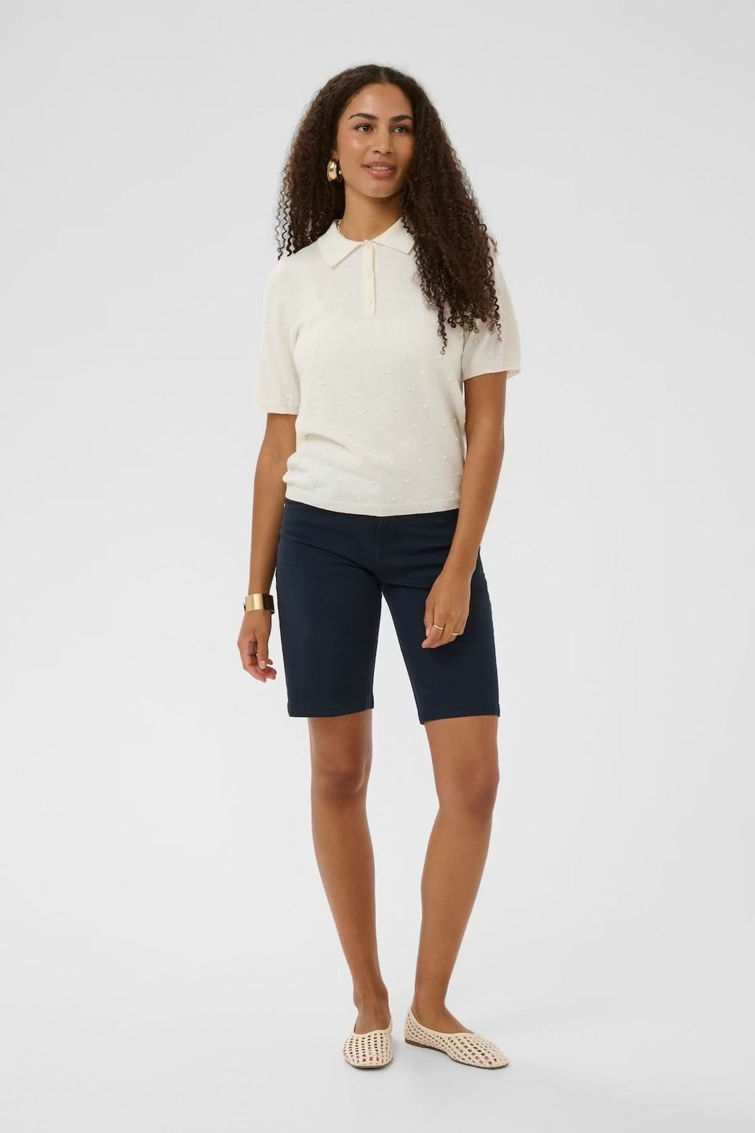Femme portant un bermuda classique coupe droite, silhouette nette, taille mi-haute, parfait pour une garde-robe estivale moderne.