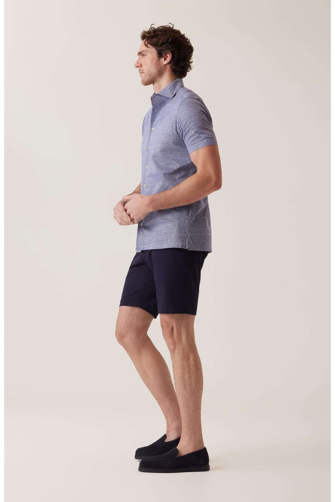 Homme portant une chemise à manches courtes et un short marine, parfait pour un look décontracté et actif.