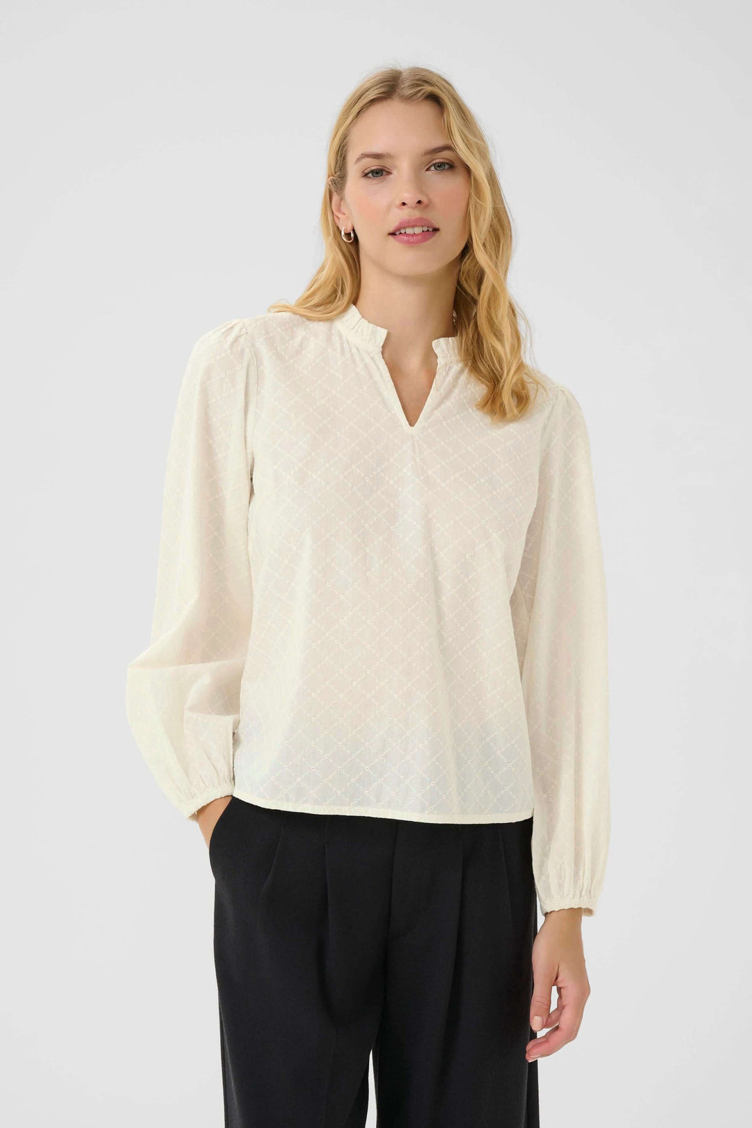 Blouse Eimy avec motif discret, encolure fendue et manches longues bouffantes, portée par une femme, style chic et féminin.