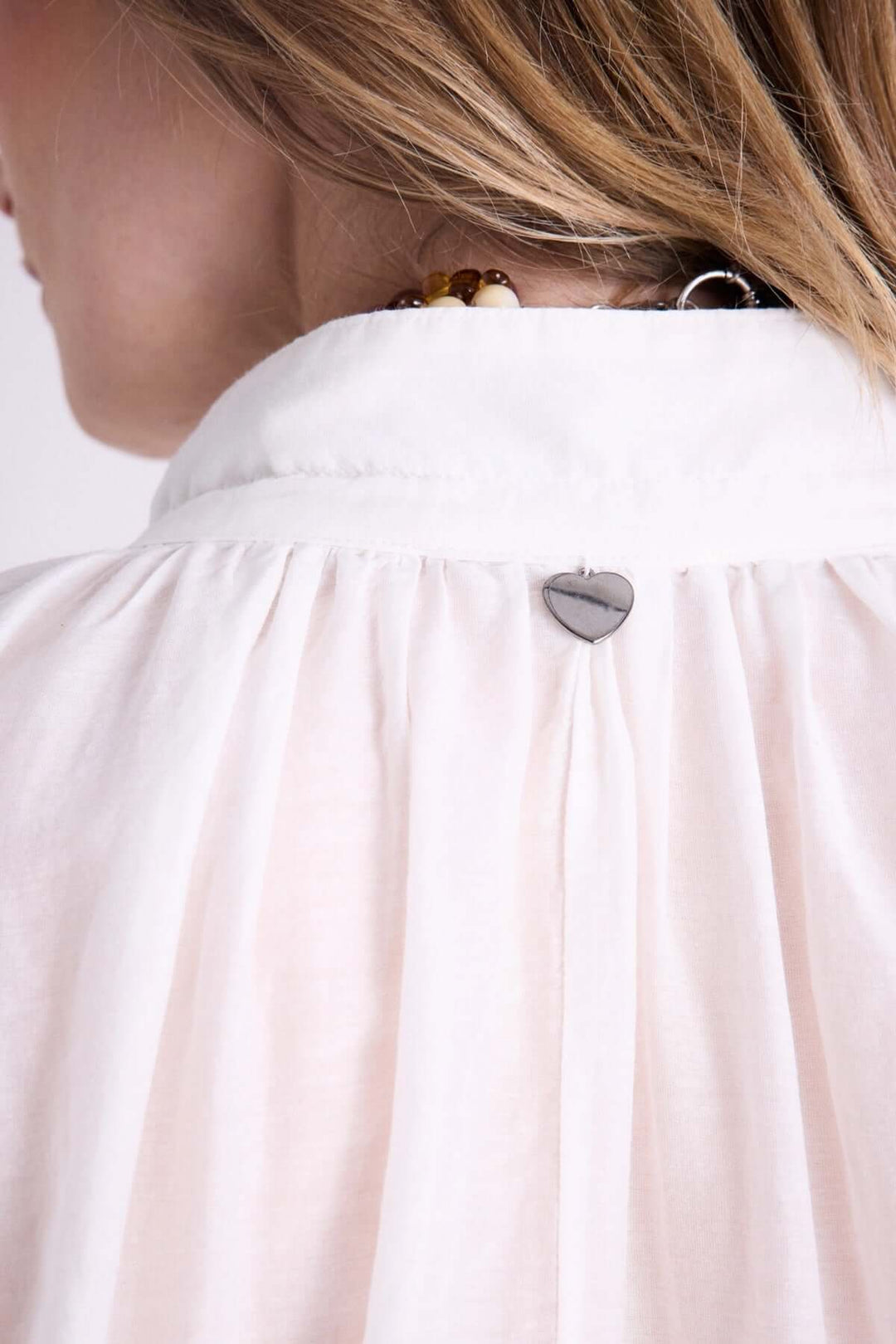 Vue arrière d'une blouse légère à capuche avec détail de cordon et bijou en forme de cœur.