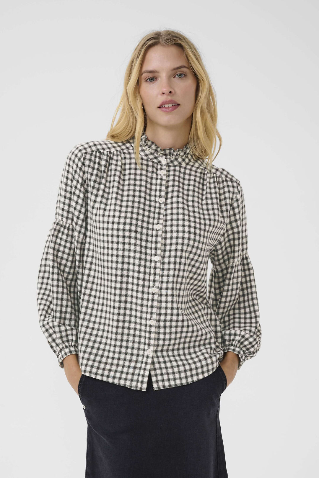 Blouse Samilla à carreaux avec col à volants, manches bouffantes et boutonnage frontal, portée par un modèle pour un look chic et intemporel.
