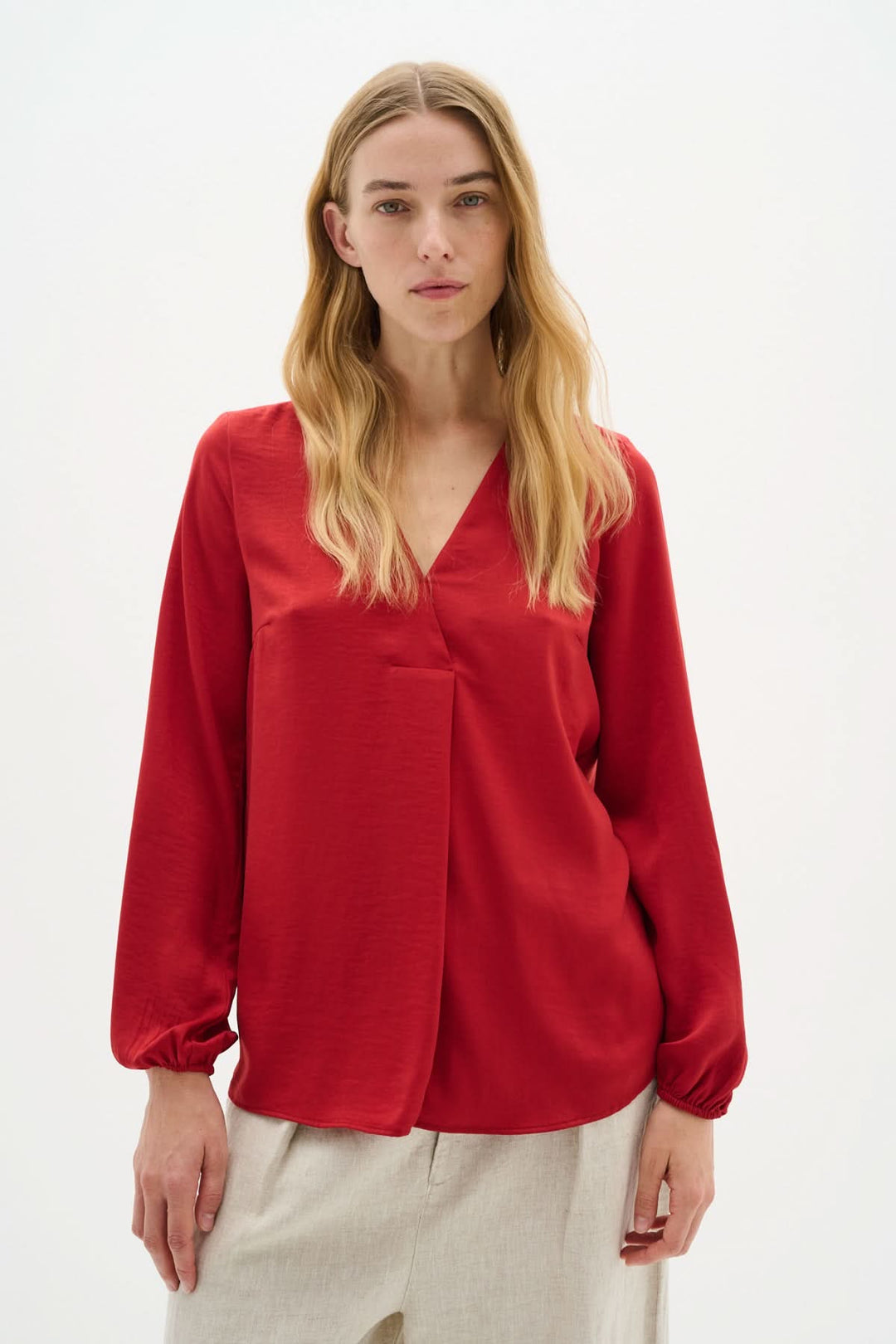 Blouse col en V Rinda rouge, ample avec manches longues et poignets ajustés, idéale pour un look sophistiqué.