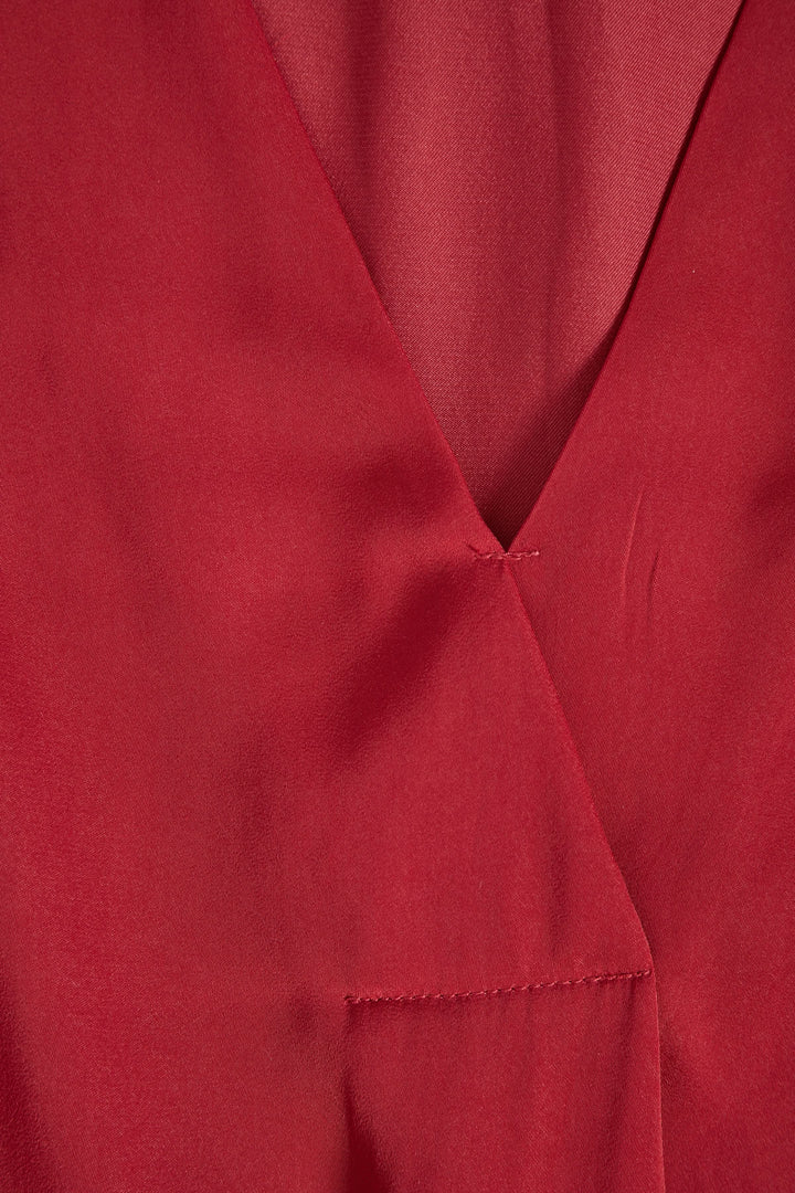 Détail d'une blouse rouge à col en V, mettant en avant la texture et la coupe ample.