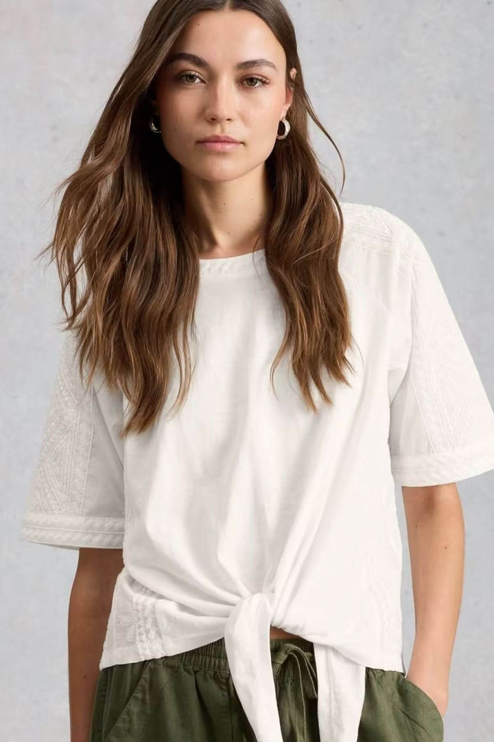 Blouse à col rond brodé avec ourlet à nœud, coupe ample et féminine, manches courtes, idéale pour un look quotidien décontracté.