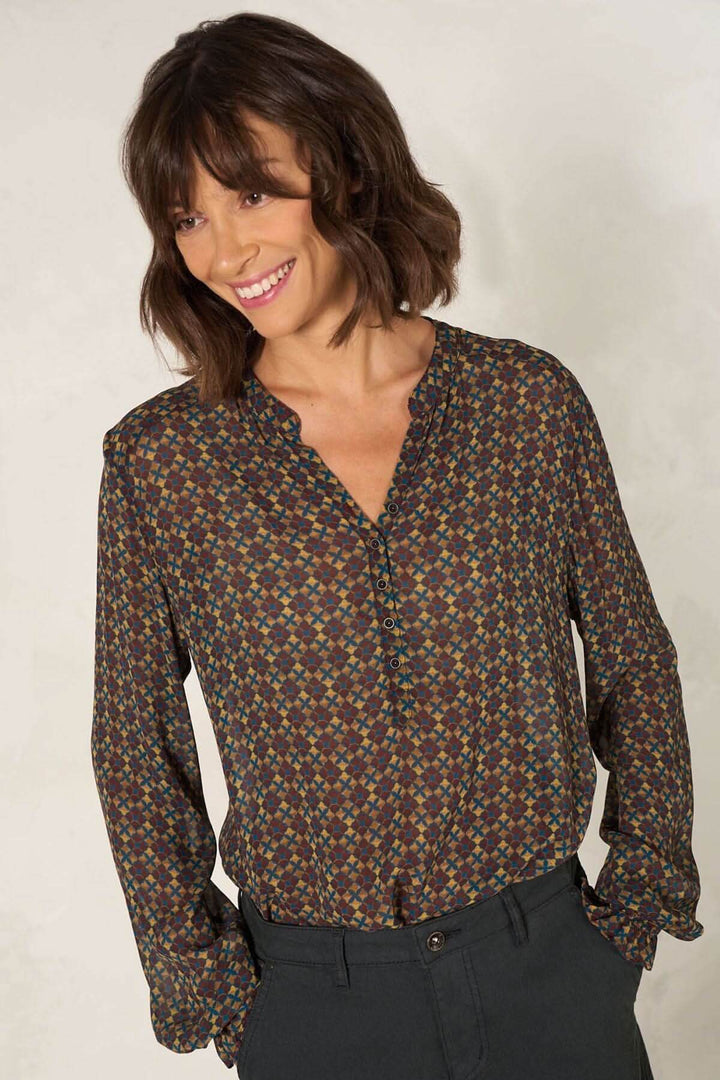 Blouse coupe droite à manches longues avec décolleté en V, imprimé coloré et bordure élastique, portée par une femme souriante.