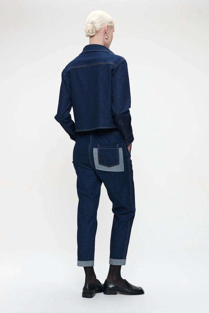Modèle portant une blouse en denim avec rabat de poche, vue arrière, style contemporain, coupe droite, contraste élégant.