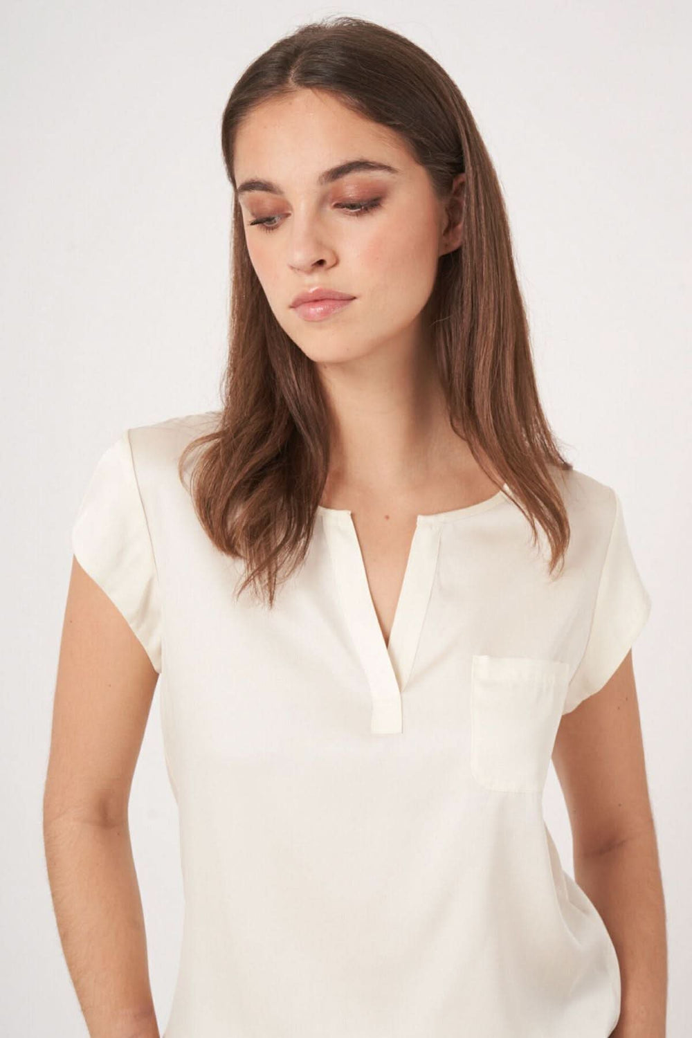 Blouse en soie légère, décolleté en V, manches coupées, couleur blanche, design élégant et décontracté.