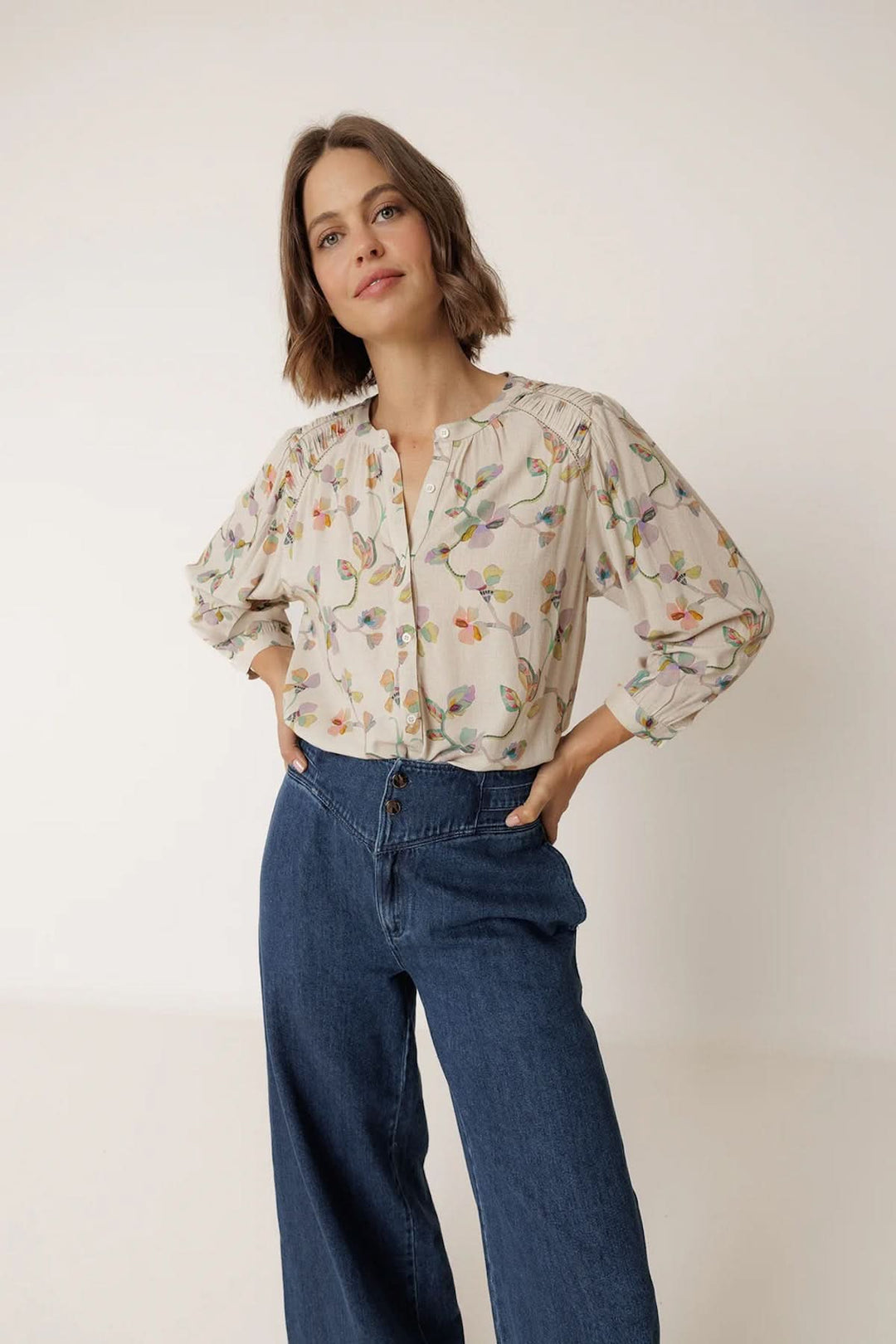 Femme portant une blouse florale à manches longues avec encolure ouverte, idéal pour un style élégant et quotidien.