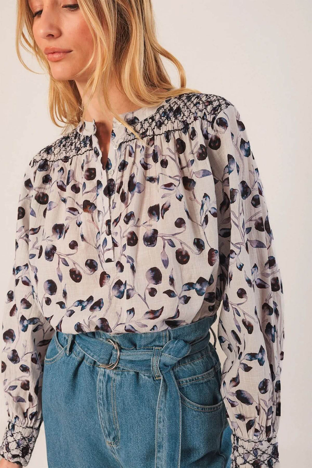 Blouse fluide à imprimé nature avec détails smockés aux épaules, portée avec un jean taille haute pour un look chic et décontracté.