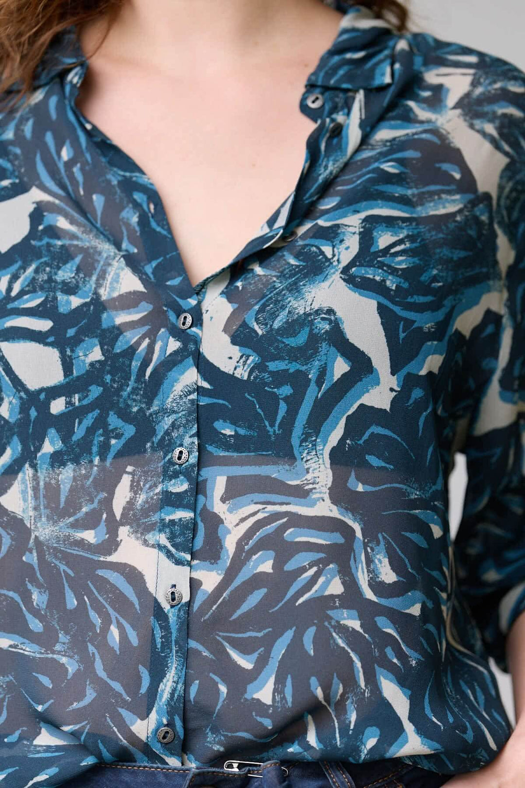 Blouse fluide à imprimé abstrait en tissu léger avec col chemise ouvert et fermeture boutonnée.