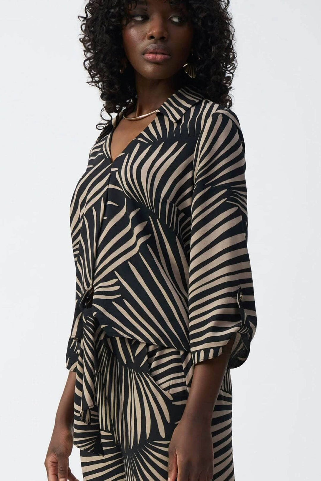 Blouse légère imprimé feuillage avec col en V, manches 3/4 et ourlet noué, style décontracté et féminin.
