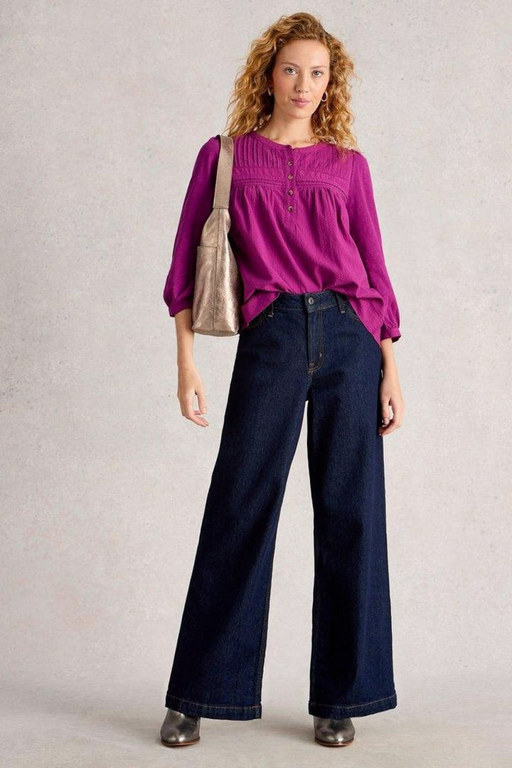Blouse plumetis à plastron froncé portée avec un jean large, style élégant et féminin.