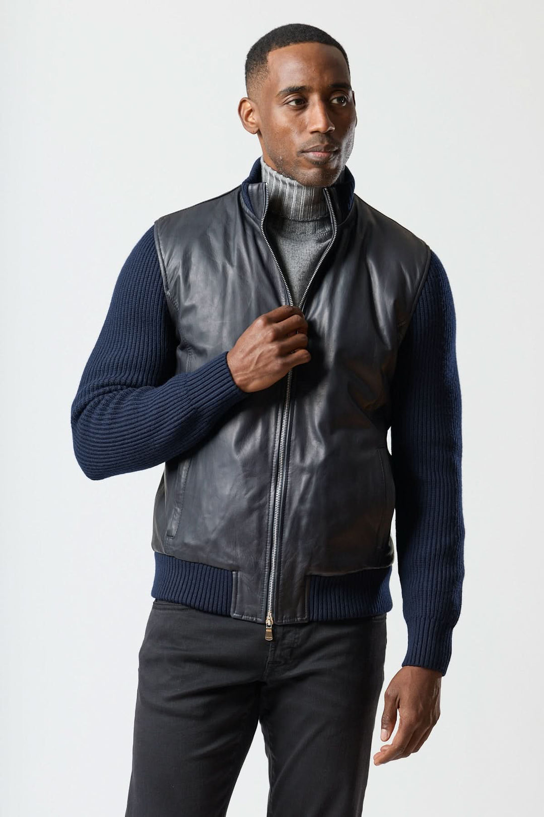 Homme portant un Blouson hybride cuir &amp; tricot zippé, combinant cuir lisse et manches tricotées pour un look moderne et polyvalent.