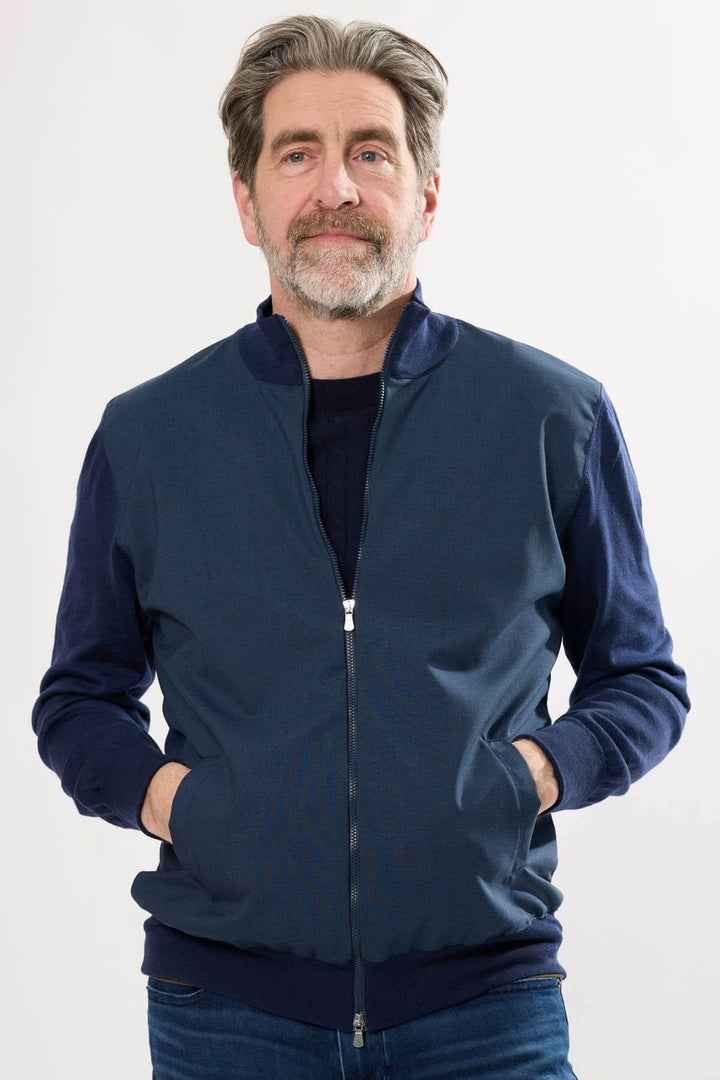 Homme portant un blouson sportif à fermeture éclair, avec manches en tricot, coloris bleu marine.