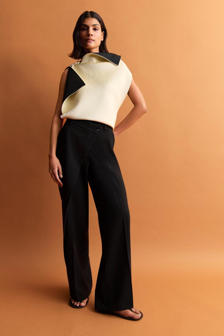 Femme portant un pantalon Anais à jambe large, avec un haut moderne, sur fond orange.