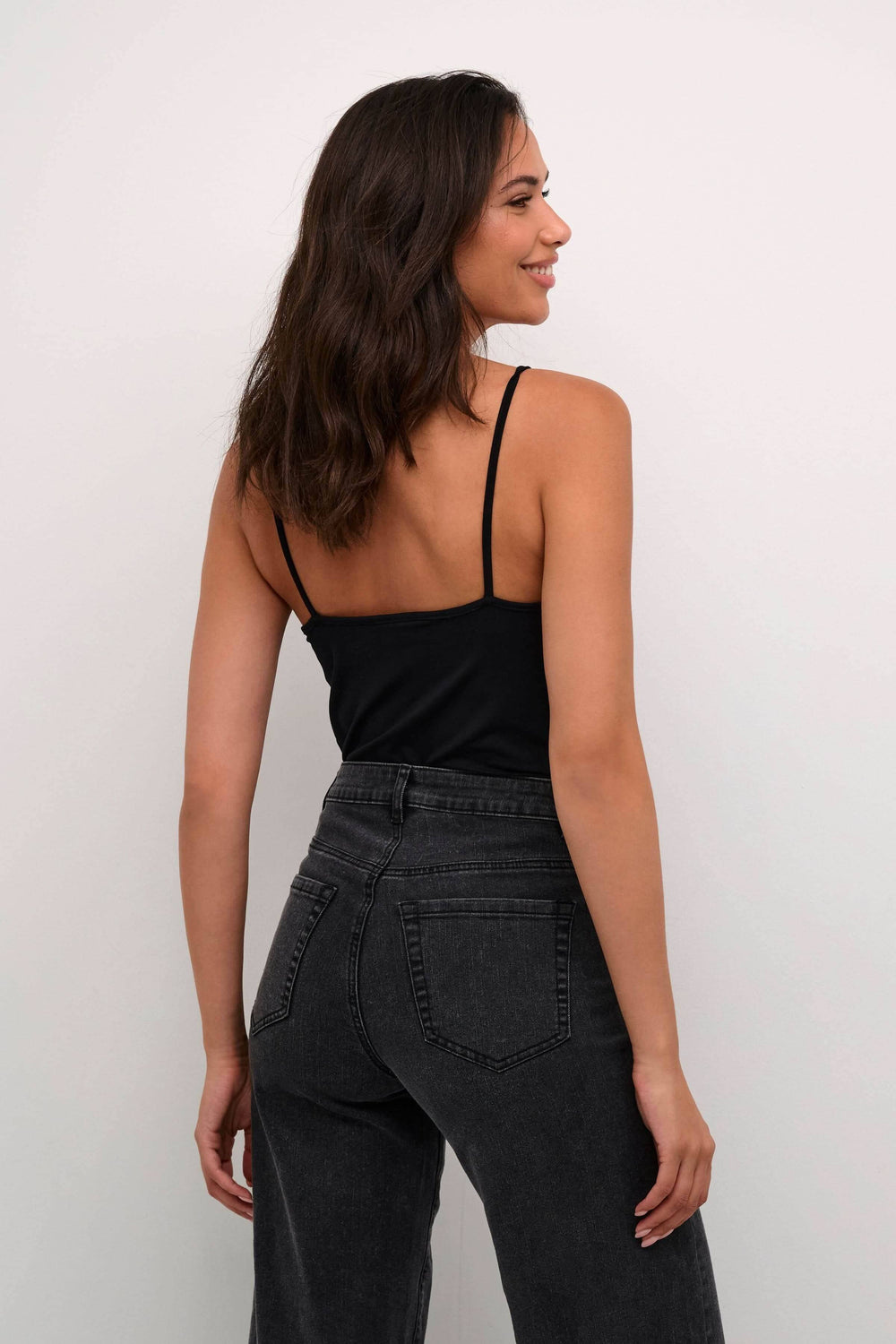 Camisole Frida à bretelles réglables, portée avec un pantalon noir, style décontracté et moderne.