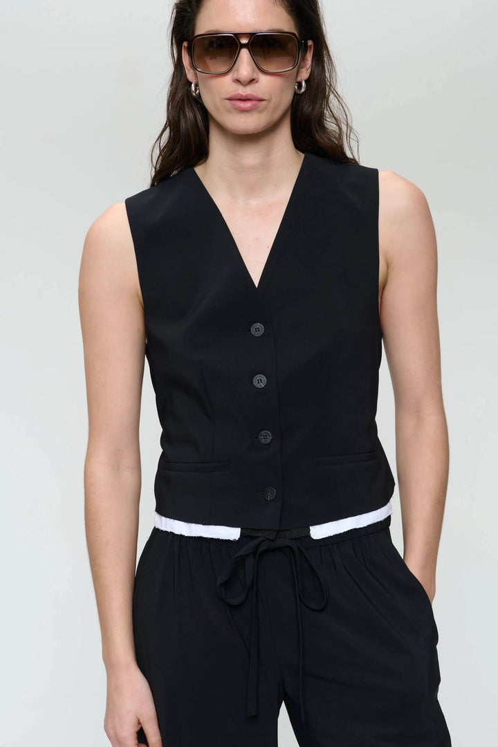 Camisole Kay noir sans manches avec col en V profond et boutons, stylée avec des lunettes de soleil.