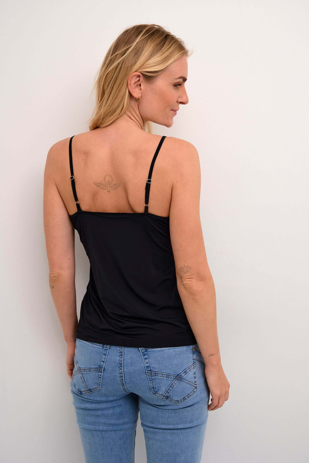 Femme portant la Camisole Lissandra noire avec fines bretelles, silhouette épurée et coupe ajustée pour un confort optimal.