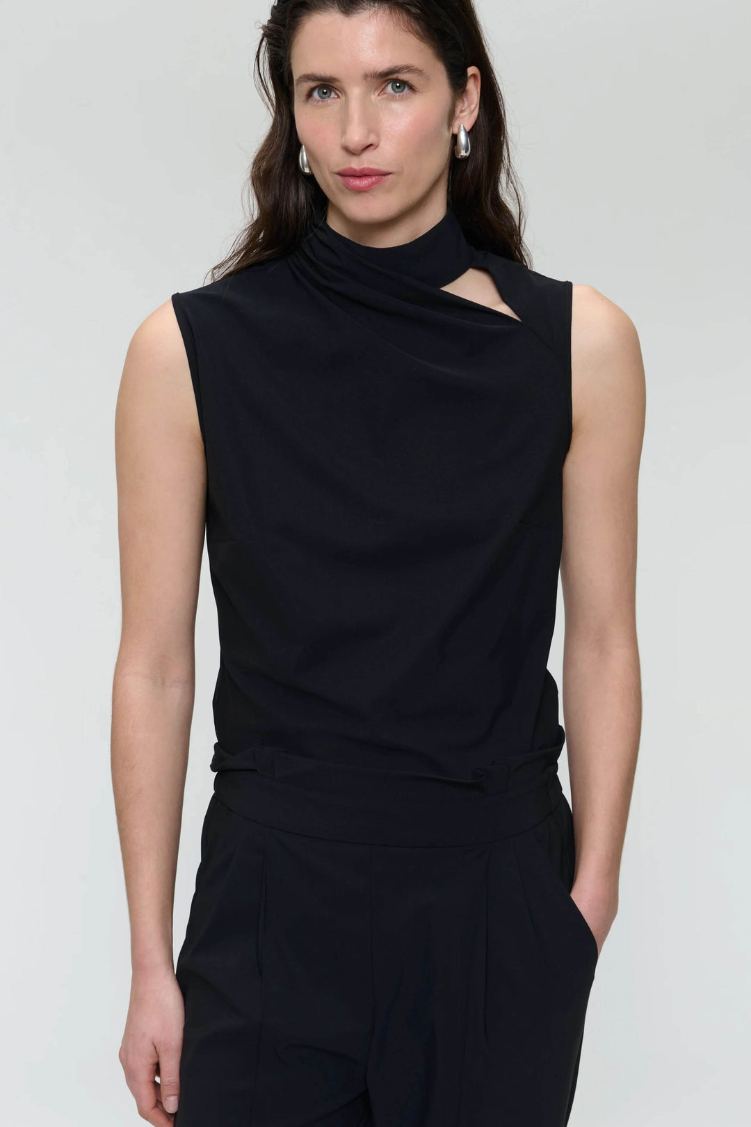 Camisole Naomi sans manches avec col drapé asymétrique et ouverture subtile, en matière extensible noire.