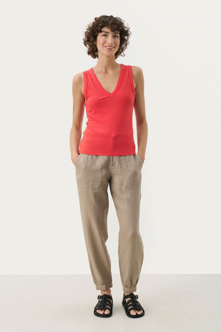 Camisole Nikkia rouge à col en V, portée avec des pantalons beiges pour un look décontracté et élégant.