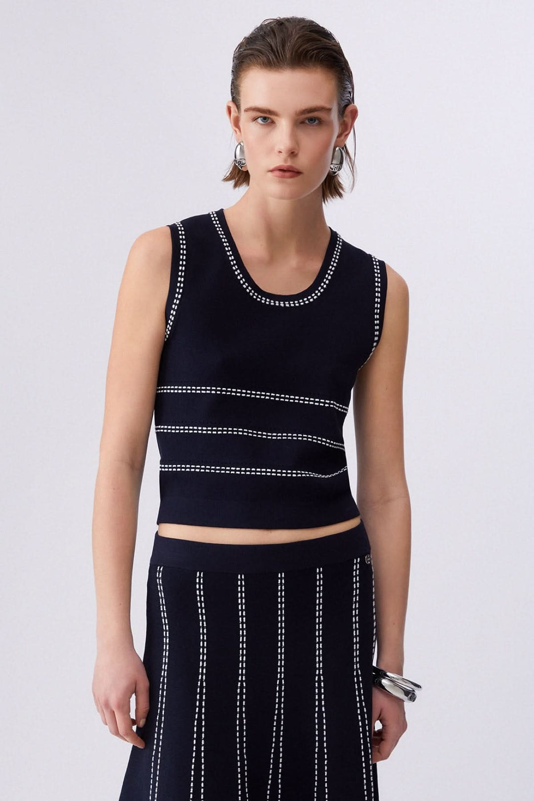 Camisole en maille sans manches à motif rayé, élégante avec encolure ronde et design moderne, portée avec une jupe assortie.