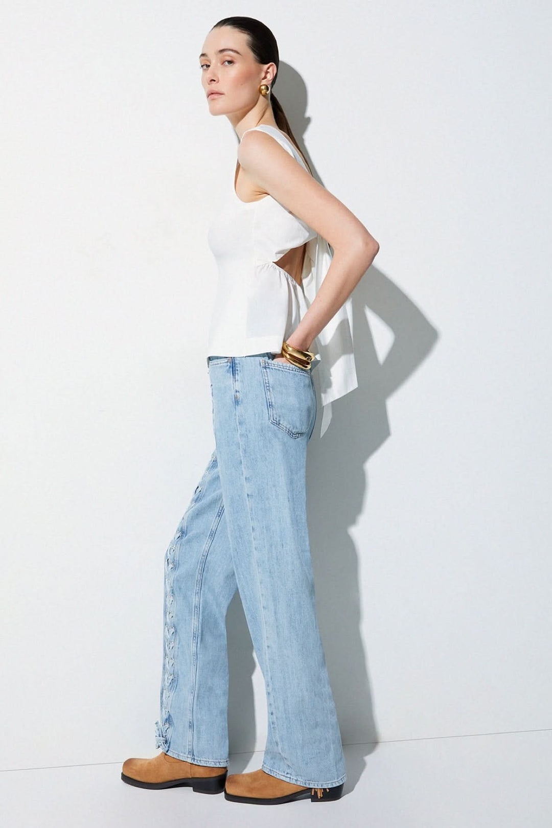 Femme portant une camisole fluide avec dos ouvert et nœud, style élégant et moderne pour une tenue raffinée.