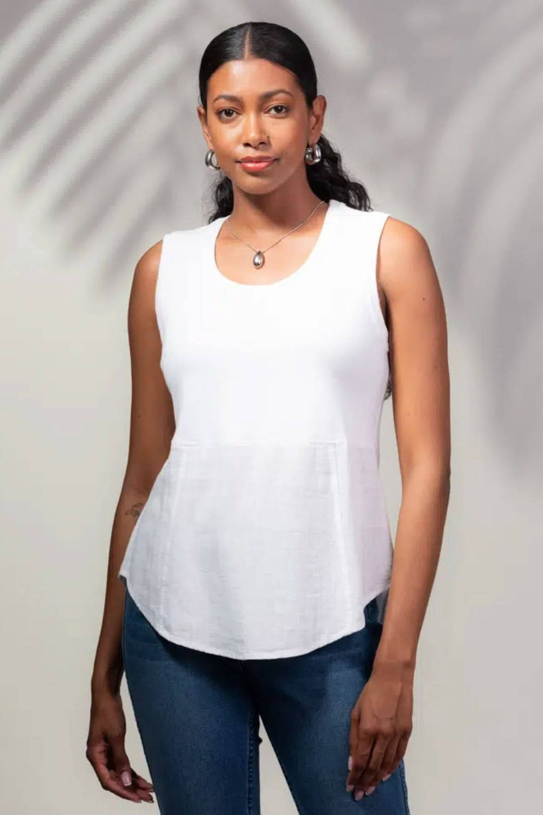 Camisole sans manches blanche avec encolure ronde et coupe légèrement évasée, portée par un modèle. Parfaite pour l'été.