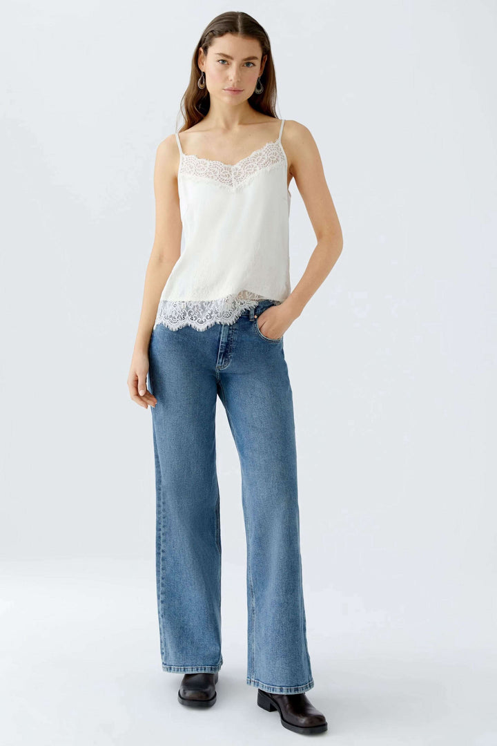 Camisole satin et dentelle avec bordure en dentelle, décolleté en V, portée avec un pantalon en denim.