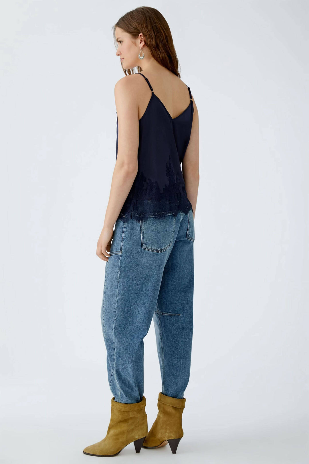 Camisole en satin noir avec bordure en dentelle, dos en V et bretelles spaghetti, portée avec un jean ample.