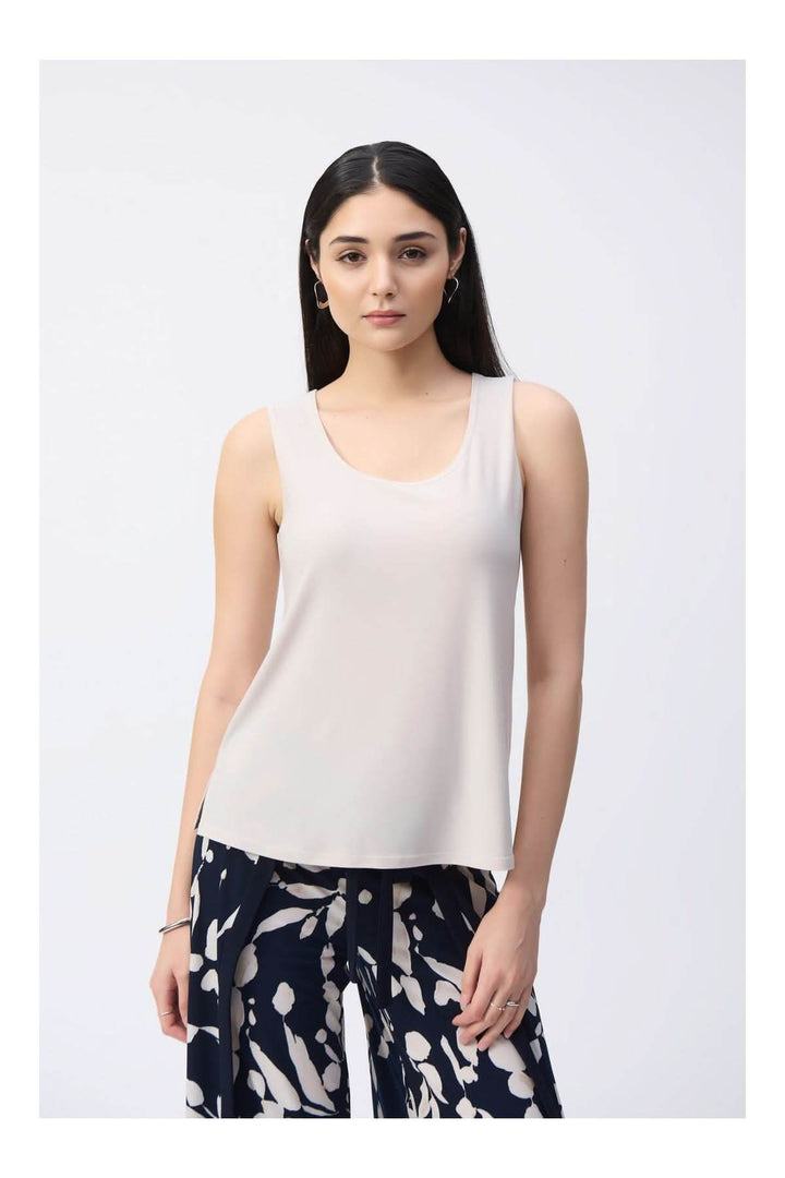 Femme portant une camisole soyeuse à col rond avec un design épuré et tissu fluide."