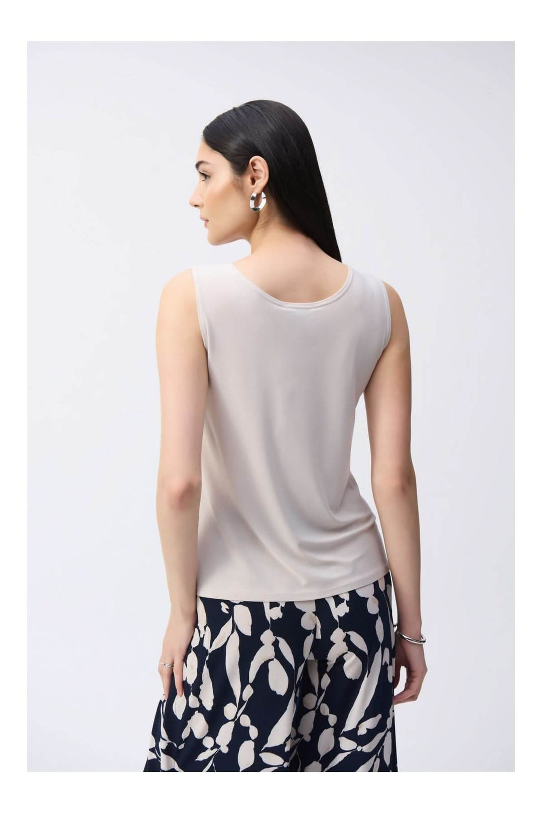 Femme portant une camisole soyeuse à col rond, design épuré et fluide, vue de dos, parfaite pour toutes les garde-robes élégantes.