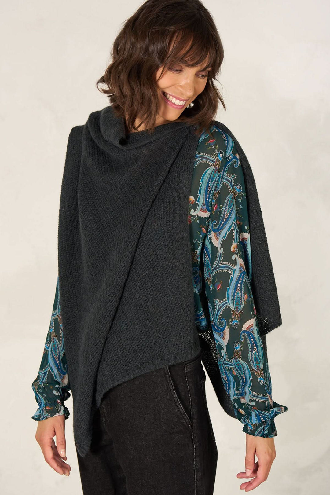 Femme portant une cape foulard tricot multifonctionnelle, légèrement transparente, avec un bouton en nacre.